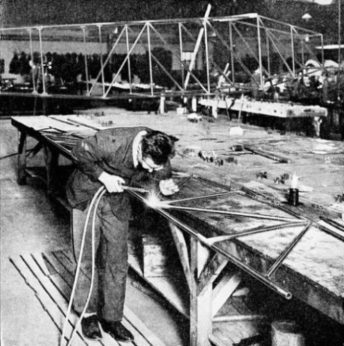 THE TUBES FORMING THE SIDE of a welded fuselage are first fitted into a jig which holds them true