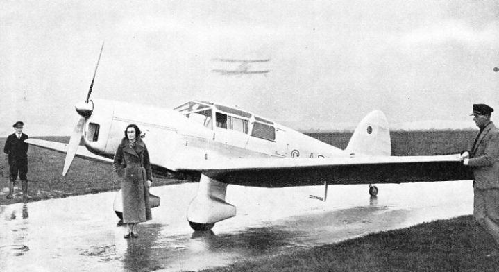 Miss Jean Batten is standing beside her Percival Gull aircraft in which she won the trophy for 1935